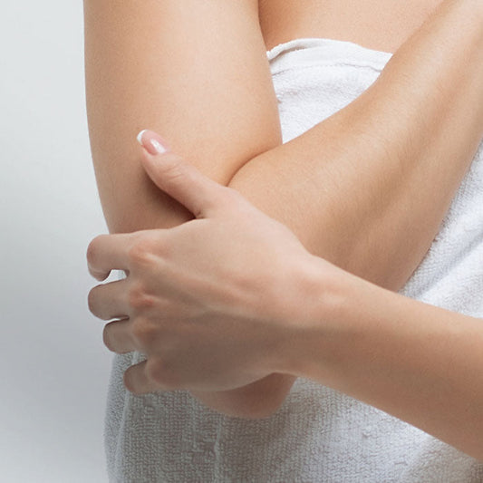 Close-up of a person's arm with a hand gently touching it against a neutral background